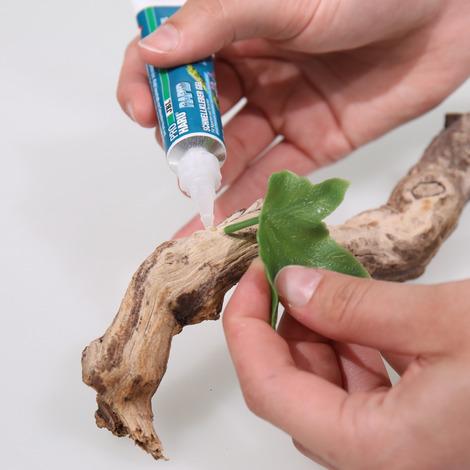 Anvendelse af akvarielim til fastgørelse af en kunstig plante på et stykke drivtræ som dekoration til akvarier.
